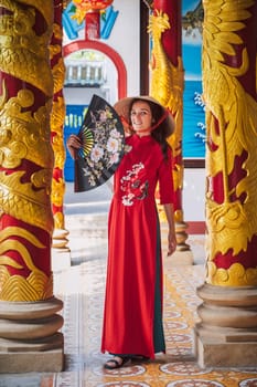 happy young tourist girl in a traditional Vietnamese hat Non La visits the landmark of Buddhist temple in Asia in Vietnam