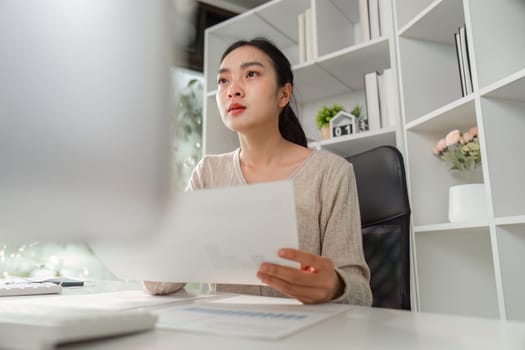 An office worker looks thoughtfully at financial reports, reflecting focus and the challenges of managing work-related stress.