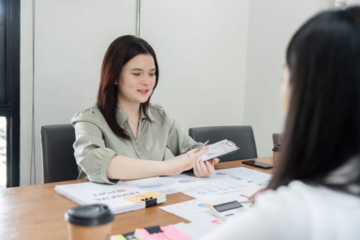 A woman presents financial strategies to her colleagues in a modern office setting, fostering collaboration and professional growth.