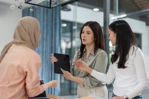 In a modern office, three engaged women share insights and strategies during a collaborative meeting.