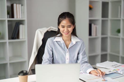 A finance worker smiles while engaging with a laptop, showcasing a positive attitude in a professional workspace.