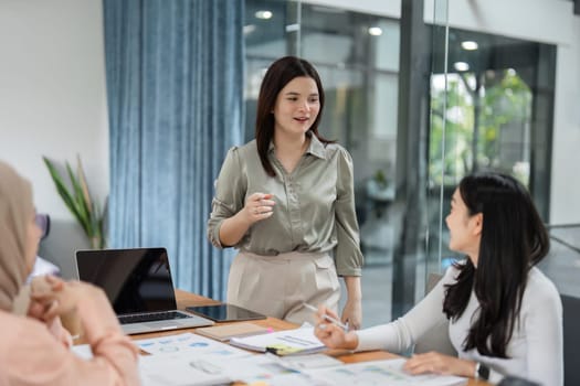A diverse group of women collaborates in an office setting, reviewing financial data and charts during a meeting.