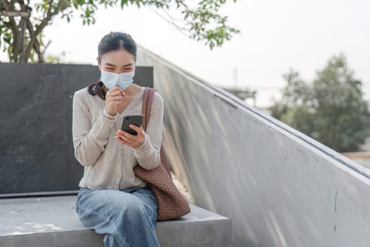 A woman wearing a mask smiles while using her smartphone, showing resilience despite pollution-related discomfort.