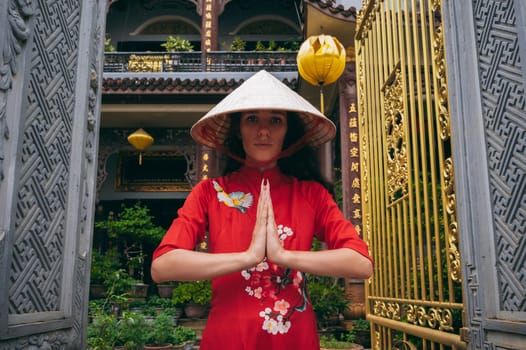 woman traveler tourist in a Vietnamese hat prays at a Buddhist temple on pagoda in Hoi An in Vietnam in Asia