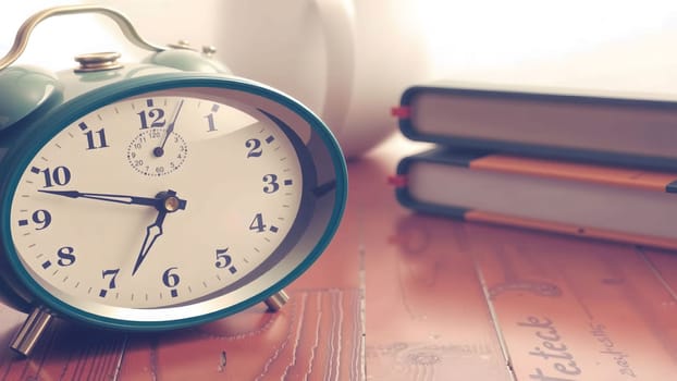 The On the table next to a bed, there is a clock and old book