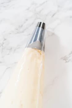 Transferring the homemade cream cheese frosting into a piping bag, ready to create beautiful and delicious decorations.