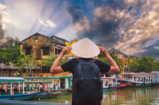 back of male tourist traveler in a Vietnamese hat on a bridge in old town in Hoi An in Vietnam in Asia