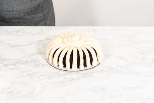 With precision, the Chocolate Bundt Cake is carefully removed from the pan - adorned with luscious cream cheese frosting, creating a delectable treat that is sure to delight.