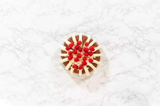 Flat lay. With precision, the White Chocolate Raspberry Bundt Cake is carefully removed from the pan - adorned with luscious cream cheese frosting, creating a delectable treat that is sure to delight.