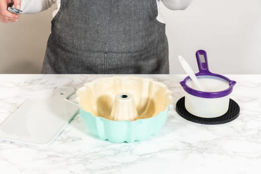To prepare the bundt cake pan for baking, a mixture of melted vegetable shortening and flour is expertly applied, ensuring easy release and a beautifully baked bundt cake.
