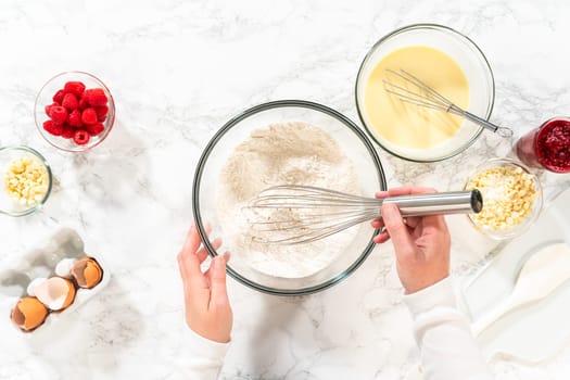 Flat lay. With a hand whisk, the measured ingredients come together - expertly mixed to prepare the cake batter for this delightful bundt cake.