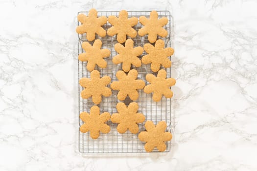 Overhead view of snowflake-shaped amber gingerbread cookies cooling on a wire rack, ready for serving or decoration.