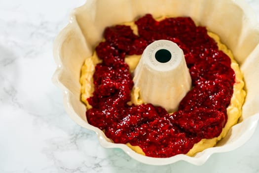 After greasing the bundt cake pan, it's time to fill it with the prepared cake batter and delightful raspberry cake filling - creating a perfect harmony of flavors.