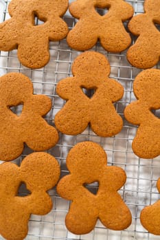 Close-up of golden-brown gingerbread men with heart-shaped cutouts cooling on a wire rack.