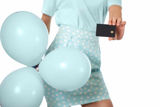 Caucasian female hand holding black premium credit bank card and blue festive air balloons on white background. digital business finance