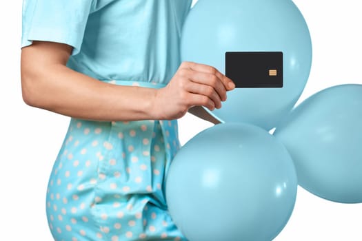 Caucasian female hand holding black premium credit bank card and blue festive air balloons on white background. digital business finance