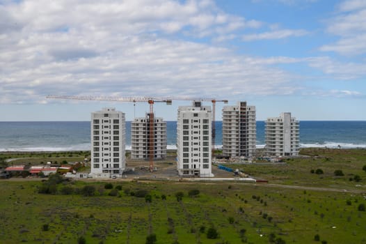 Construction of modern apartments occurs near the shoreline, showcasing urban development against a natural backdrop.
