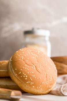 Empty burger bun with sesame seeds on a kitchen table.