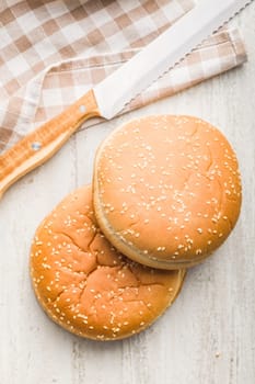 Empty burger bun with sesame seeds on a kitchen table.