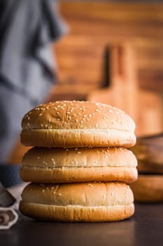 Empty burger bun with sesame seeds on a black table.