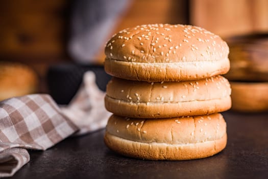 Empty burger bun with sesame seeds on a black table.