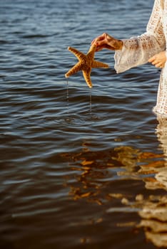 Hand holding starfish with beautiful tropical summer sand beach island, relaxing vacation summer blue sea concept. High quality photo