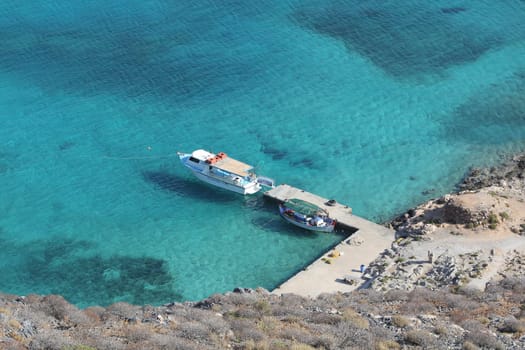 Boat at the pier top view, clear blue water in Greece, near the rocks