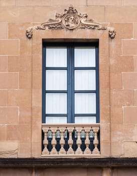 A beautifully crafted window with ornate columns and decorative motifs showcases classic architecture in a city building.