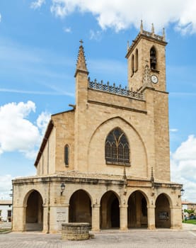 The historic church in Obanos features stunning architecture and a prominent clock tower against a vibrant sky.