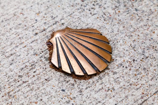 This bronze shell is set into a stone pathway, marking a trail at a significant pilgrimage location.