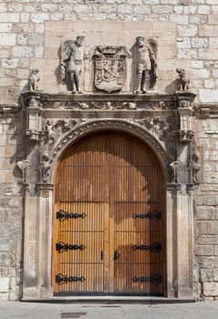 An ornate wooden door featuring intricate stone carvings and sculptures, highlighting Burgos' rich history and artistry.