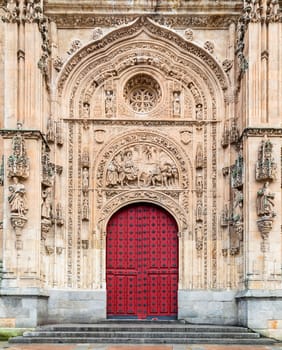The ornate entrance of Salamanca Cathedral features intricate carvings and a striking red door, highlighting its architectural beauty.