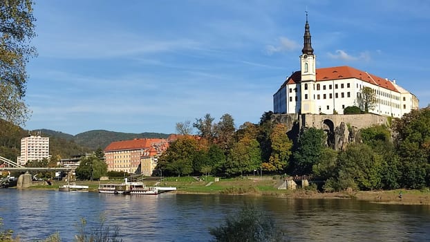 Castle riverside trees green nature summer autumn background landscape blue sky day. October 16 2024 Decin Czech Republic Europe travel places . High quality photo park outdoor historic buildings