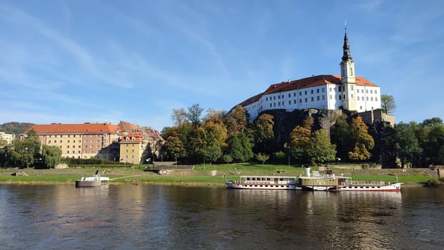 Castle riverside trees green nature summer autumn background landscape blue sky day. October 16 2024 Decin Czech Republic Europe travel places . High quality photo park outdoor historic buildings