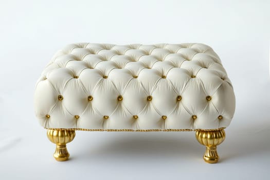 Luxurious ottoman features a tufted design in white upholstery complemented by ornate gold legs, perfect for any upscale space.