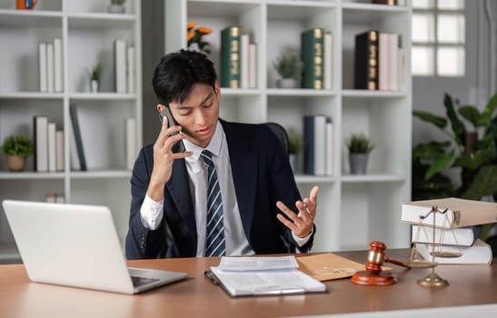A young businessman is engaged in a phone conversation about important matters while reviewing documents, demonstrating professionalism in a contemporary office setting.