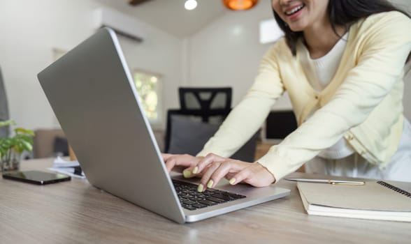 A dedicated business professional types on a laptop while reviewing documents, demonstrating focus and multitasking at home.