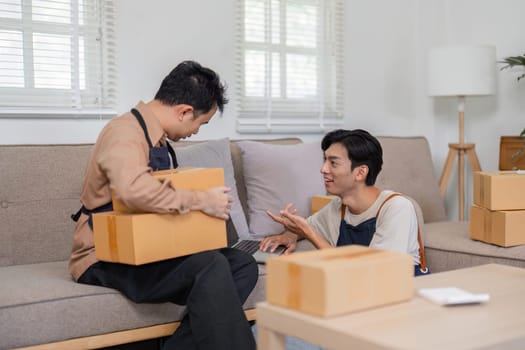 In a cozy living room, two online sellers collaborate on packaging and delivery methods, surrounded by boxes and a laptop.