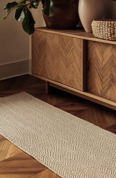 A long natural fiber runner lays on a wooden floor beside a stylish cabinet adorned with plants and woven decor.