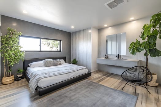 This stylish bedroom features a large bed, indoor plants, and ample natural light, creating a serene and comfortable atmosphere for relaxation.