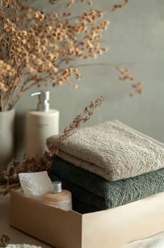 Soft towels are neatly arranged in a wooden box with a natural decor background, creating a calming spa atmosphere.