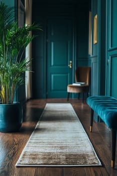 A stylish hallway features a soft rug, a plant in a pot, a teal bench, and a chair against walls painted in a rich green color.