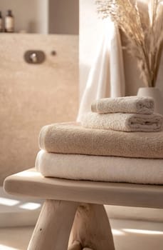 A serene bathroom with neatly stacked soft towels on a wooden surface, creating a calming atmosphere. Natural light highlights the textures.