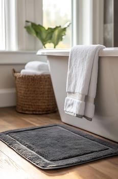 Soft towels hang next to a modern tub, with a plush rug and woven basket enhancing the relaxing atmosphere of the bathroom.