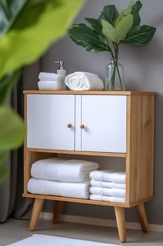 A wooden cabinet displays neatly folded towels and a vase with greenery, adding a touch of elegance to the modern interior decor.