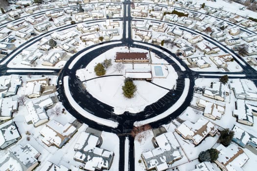A snow covered neighborhood with a large circle in the middle. The circle is surrounded by houses and a pool