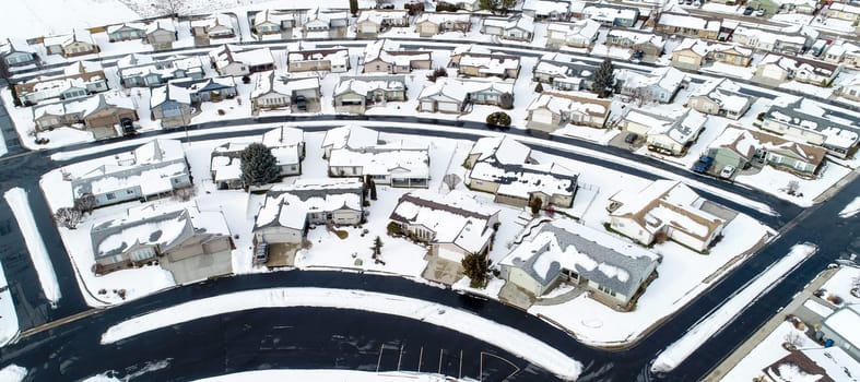 A snowy residential area with houses and a street. The houses are covered in snow and the street is covered in snow as well