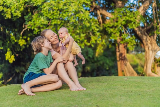 Young mother, teenage son, and one-month-old baby enjoying quality family time in the park. Multigenerational bonding and outdoor family love concept.