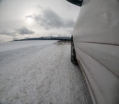 Car traveling down a slick road that is covered in snow