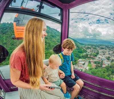 Mother and two sons on a cable car ride in Orizaba, Mexico. Scenic family adventure with panoramic views of the city, lush mountains, and iconic landscapes. Concept of family bonding, travel, and exploration in nature.